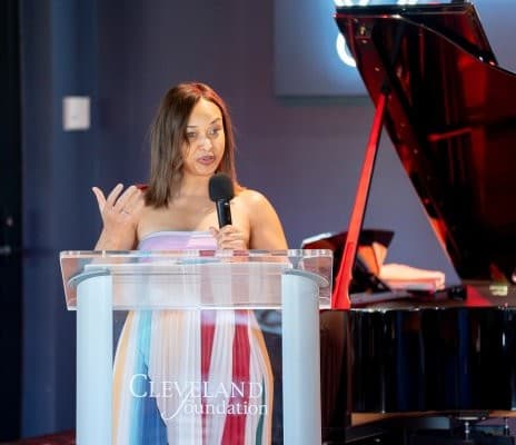 Nina Kidd seated at the piano in a dimly lit event space, spotlight illuminating the performance area